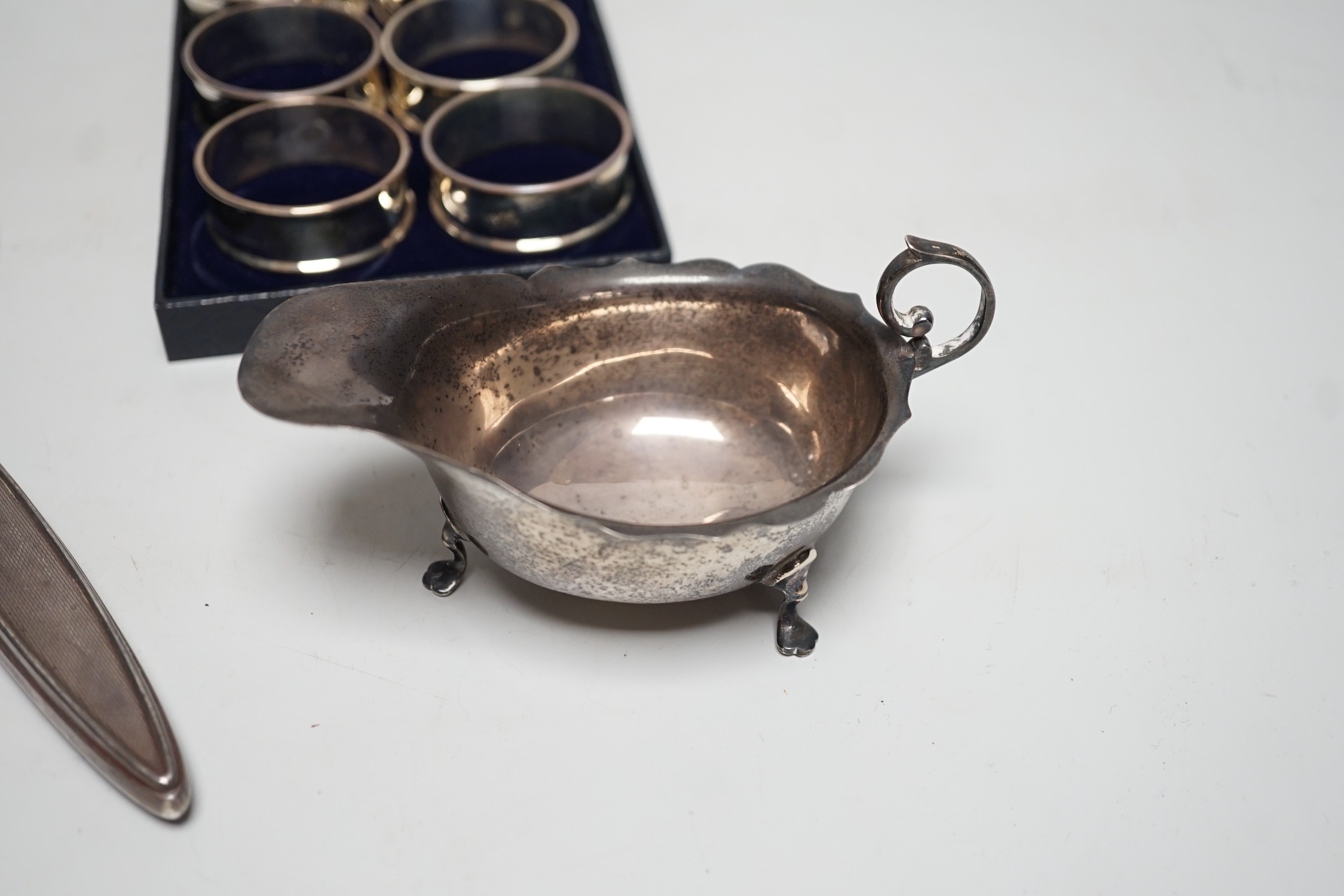 A set of six modern silver napkin rings, a George V silver sauceboat and a silver mounted hand mirror.